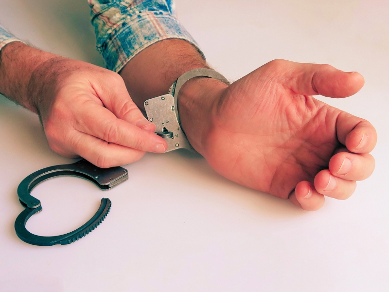 The criminal is released from prison. The acquittal was handed down to an innocent defendant. Hands unbuckling handcuffs. Open handcuffs on the male hands of the arrested person