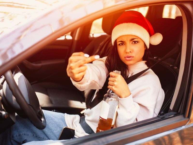 Fuck yourself Happy New Year and Merry Christmas An angry Drunk woman is sitting in a car, she is dressed in a red Santaclaus hat and shows the middle finger to the camera. Fuck yourself