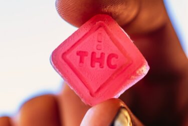 Female model holding a thc edible between her fingers