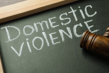 Blackboard with words DOMESTIC VIOLENCE and gavel on table