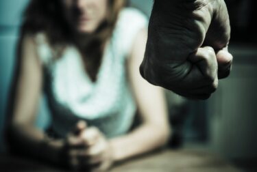 Man's hand balled in a fist and a woman is waiting for him to strike her