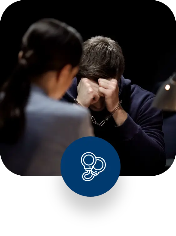 Man in handcuffs covering his face while talking to a lawyer