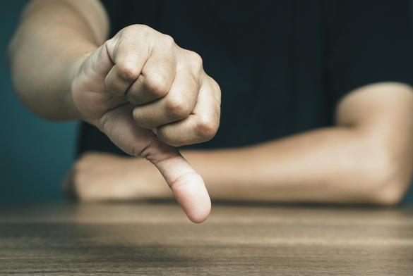 Negative concept. Close-up of young man's hand showing a thumbs down for dislike service. Customer service and satisfaction surveys concept