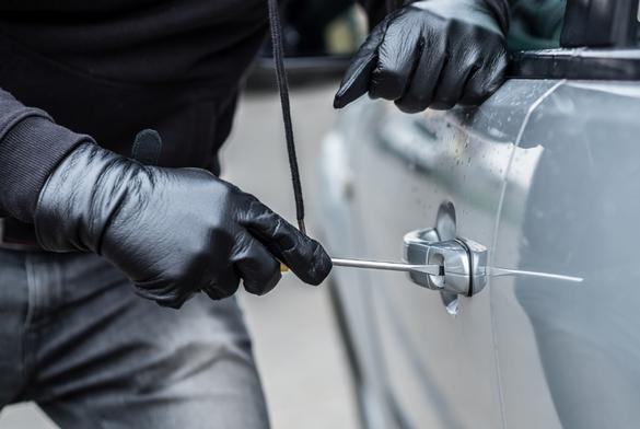 Car thief trying to break into a car with a screwdriver. Car thief, car theft.