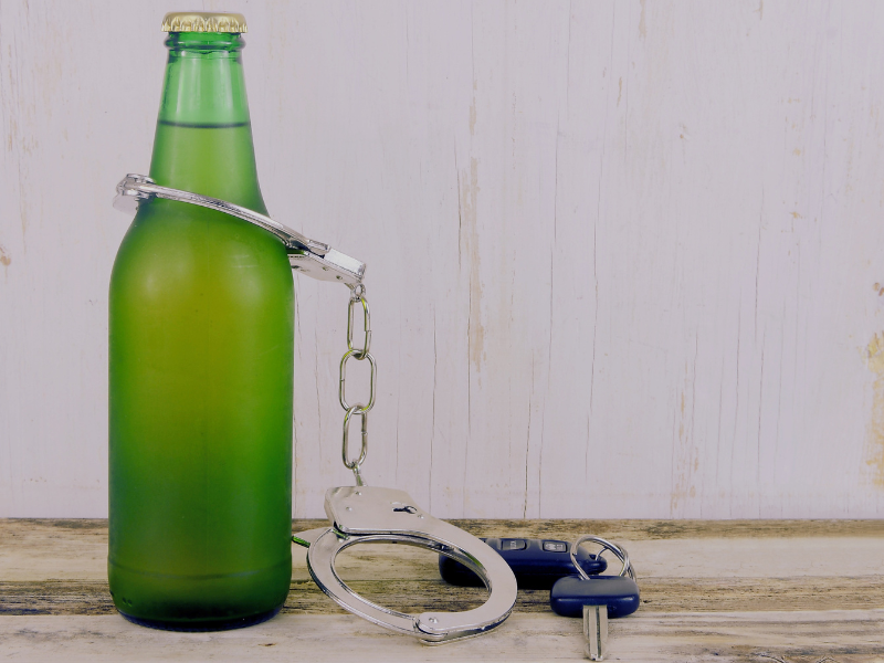 A single beer in a green bottle on a wooden table with rustic wooden background