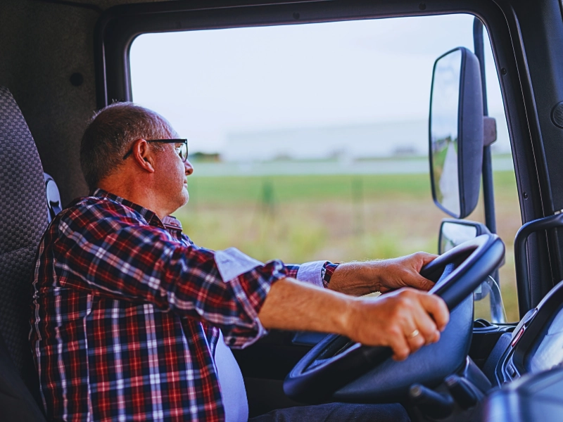 Senior truck driver holding a wheel and looking through the window. DWI Affects CDL Holders