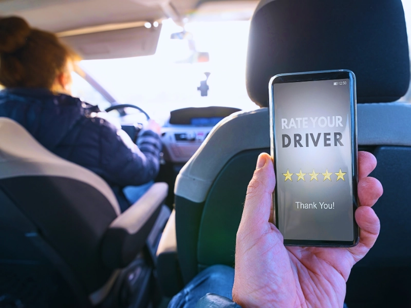 Passenger is sitting on the back seat of the car and using smart phone app to rate a driver. DWI Affects Rideshare Drivers