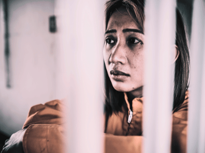 A worried-looking woman locked in a police cell.